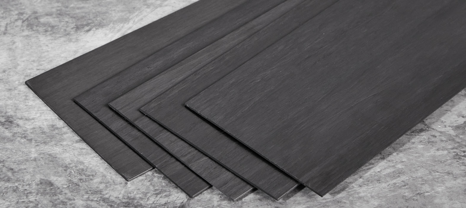 Why are carbon fiber laminates used to strengthen conventional structural materials?